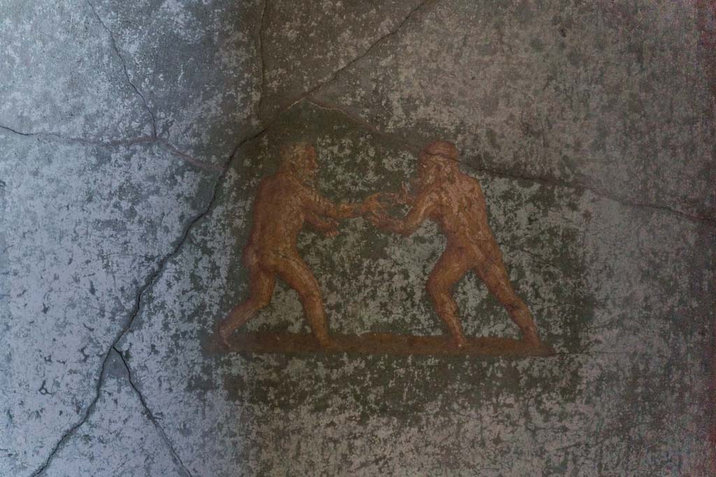I.10.4 Pompeii. April 2022. Room 48, detail of two painted athletes from west end of south wall. Photo courtesy of Johannes Eber.
