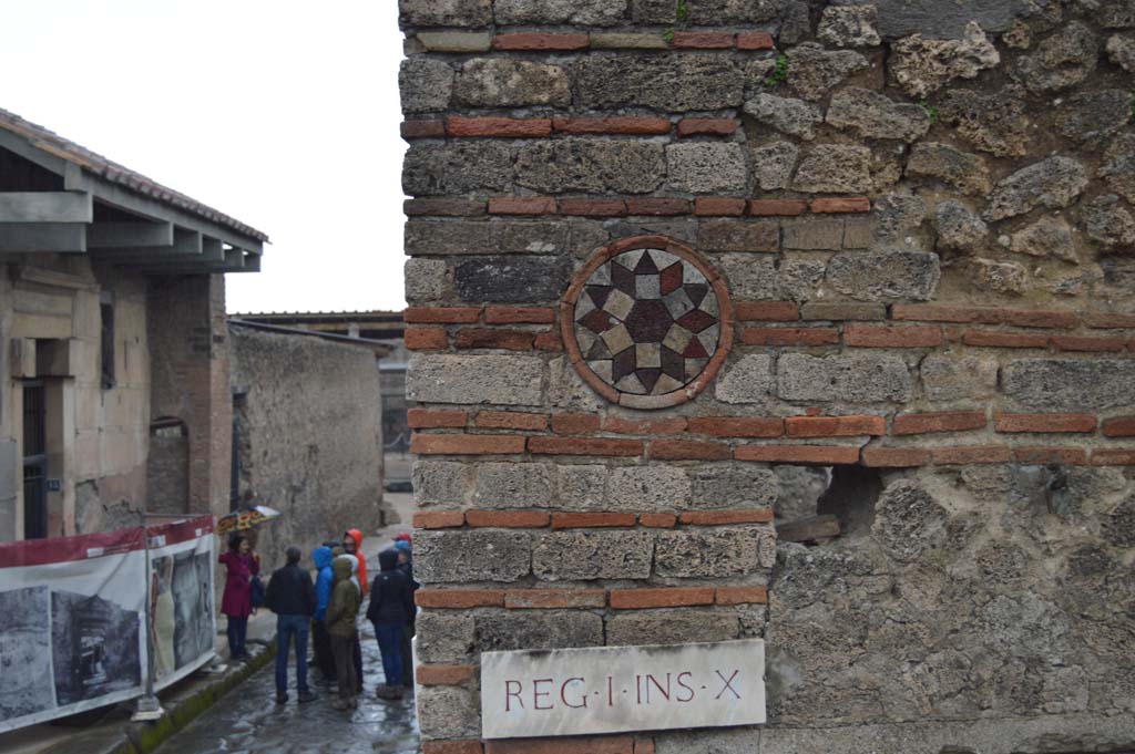 I.10.9 Pompeii. March 2018. 
Looking towards coloured terracotta plaque above doorway of I.10.9, and east along Vicolo del Menandro, on left.
Foto Taylor Lauritsen, ERC Grant 681269 DCOR.
