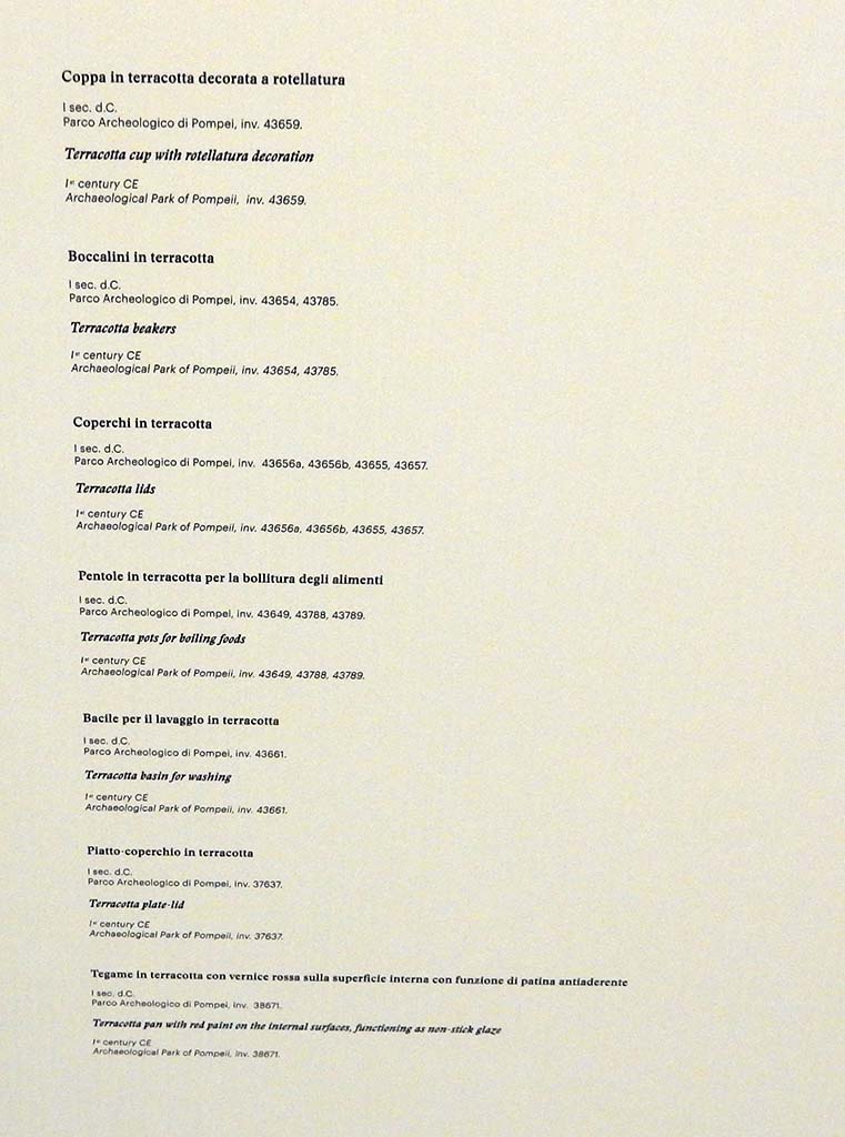 I.14.12, Pompeii. May 2018. Room 13, display notice on cabinet. Photo courtesy of Buzz Ferebee
Terracotta cup with rotellatura decoration (Coppa in terracotta decorata a rotellatura), inv. no.43659
Terracotta beakers (Boccalini in terracotta), inv. nos. 43654, 43785
Terracotta lids (Coperchi in terracotta), inv. nos. 43656a, 43656b, 43655, 43657
Terracotta pots for boiling food (Pentole in terracotta per la bollitura degli alimenti), inv. nos. 43649, 43788, 43789
Terracotta basin for washing (Bacile per il lavaggio in terracotta), inv. no.43661
Terracotta plate lid (Piatto coperchio in terracotta), inv. no. 37637
Terracotta pan with red paint on the internal surfaces, functioning as non-stick glaze 
(Tegame in terracotta con vernice rossa sulla superficie interna con funzione di patina antiaderente), inv. no. 38671
All inventory numbers are from Parco Archeologico di Pompei.
