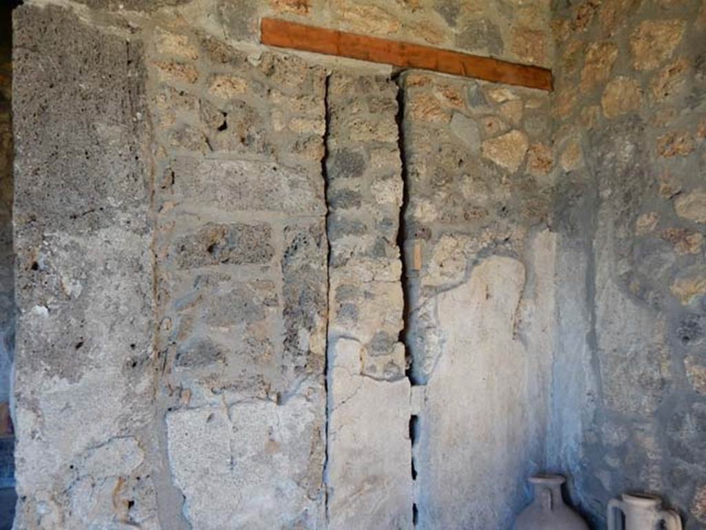 I.14.12/13, Pompeii. May 2018. Room 32, east wall behind amphorae in south-east corner of east portico. Photo courtesy of Buzz Ferebee.
