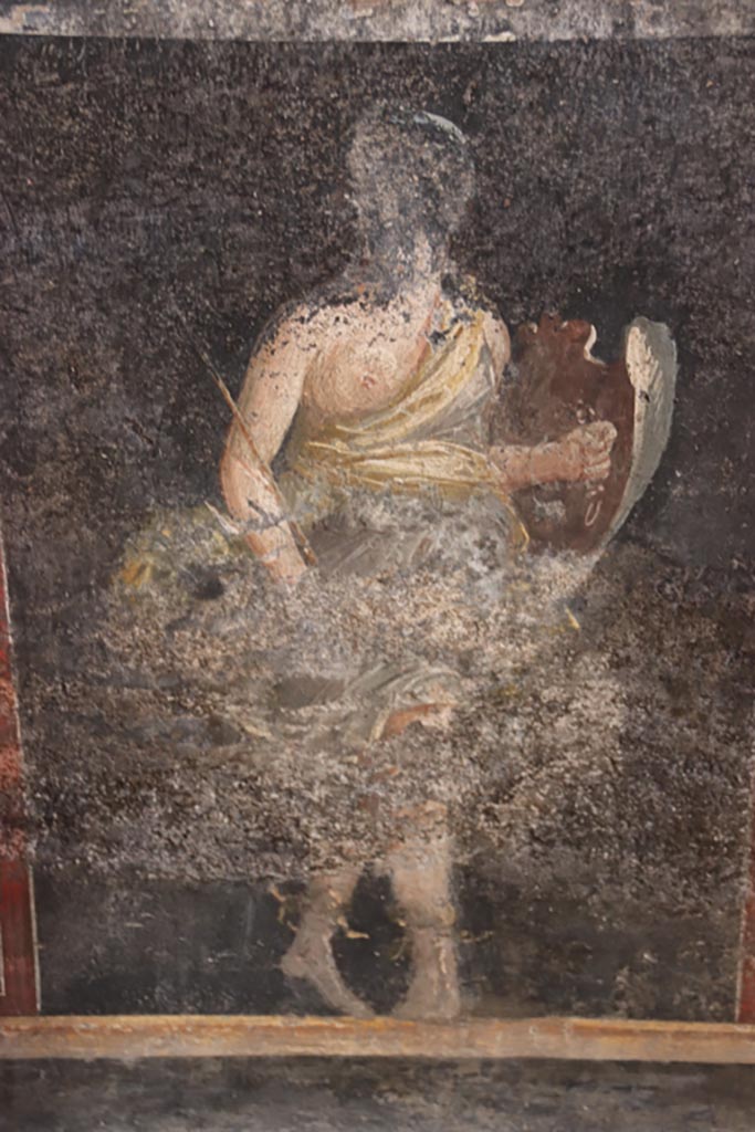 VI.15.1 Pompeii. October 2023. 
Zoccolo on lower east wall on north side of central panel, figure of an Amazon armed with a shield. 
Photo courtesy of Klaus Heese.

