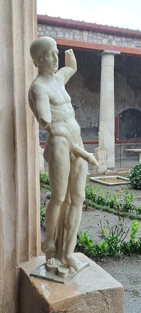 VI.15.1 Pompeii. January 2023. 
Statue of Priapus displayed on east side of peristyle. Photo courtesy of Miriam Colomer.
According to Sogliano –
“Found in the kitchen were two marble statues, both of which without doubt belonged to the decoration in the peristyle.”
See Sogliano, A. La Casa dei Vettii in Pompei in Mon. Ant. 1898, (p.269).


