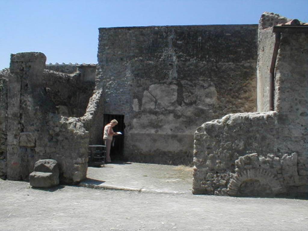VI.16.6 Pompeii. May 2005. Looking west towards entrance doorway to wide room of fullonica. According to Sogliano, the entrance doorway threshold was made of lava. In the left half could be seen a longitudinal track for fixing a board for closure, in the other half (the right side) the track was missing and the remains of a hinge proved that there had been a movable shutter of a door there. In the south-west corner of the west wall is a doorway into what now appears to be a corridor leading to VI.16.7. According to Sogliano, this actually led into a narrow room which was under the stairs from the peristyle of VI.16.7. See Notizie degli Scavi di Antichit, 1906, p. 350.



