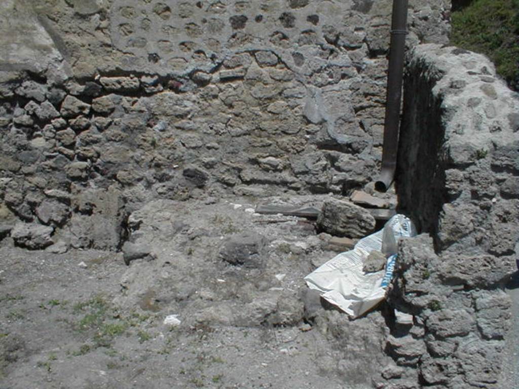 VI.16.6 Pompeii. May 2005. North-east corner of fullonica, with structure, possibly remains of tub or basin. According to Sogliano, the walls were undecorated at the bottom to the height of the dado, and then above were crudely painted in white.  Leaning against the north wall would have been a wooden ladder, which probably led up to some rooms at the top of the House of the Golden Cupids. Also against the north wall were a masonry structure with two steps.  To left were the remains of three low walls, arranged like fullonica tanks for treading pigment into cloth. Also there were the remains of a shallow tank. See Notizie degli Scavi di Antichit, 1906, p. 350.
