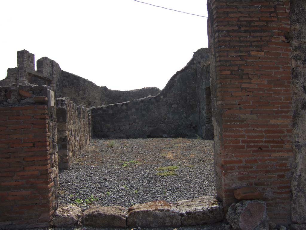 VII.7.19 Pompeii. September 2005. Looking south from entrance directly into atrium.
According to Eschebach, in the middle of the south wall would have been a lararium.
On the left can be seen doorways to an oecus with stairs to upper floor, and a triclinium fenestratum.
See Eschebach, L., 1993. Gebäudeverzeichnis und Stadtplan der antiken Stadt Pompeji. Köln: Böhlau. (p.302)
According to Boyce –
in the centre of the south wall of the large central room was a rectangular niche; in the west wall, near the floor, was an arched niche.
The latter was called the lararium by Fiorelli, although the former was more like the usual shrine.
See Boyce G. K., 1937. Corpus of the Lararia of Pompeii. Rome: MAAR 14. (p.68, no.300) 
