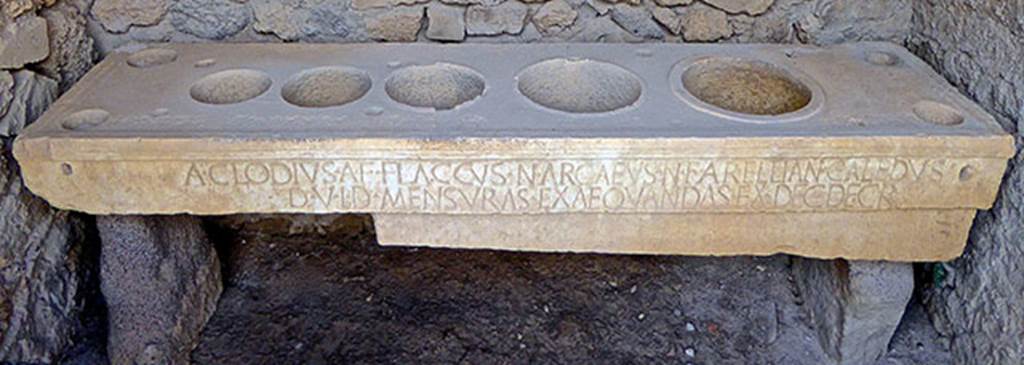 VII.7.31 Pompeii. September 2016. Mensa Ponderaria, with inscription on the front.
Photo courtesy of Michael Binns.
Original now kept in Naples Archaeological Museum. Inventory number 3828.

According to Epigraphik-Datenbank Clauss/Slaby (See www.manfredclauss.de), it read 

A(ulus) Clodius A(uli) f(ilius) Flaccus N(umerius) Arcaeus N(umeri) f(ilius) Arellian(us) Caledus
d(uum)v(iri) i(ure) d(icundo) mensuras exaequandas ex dec(urionum) decr(eto)      [CIL X 793]

According to Cooley this translates as:
Aulus Clodius Flaccus, son of Aulus, and Numerius Arcaeus Arellianus Caledus, son of Numerius, duumvirs with judicial power, saw to the standardization of the measures in accordance with a decree of the town councillors.
See Cooley, A. and M.G.L., 2004. Pompeii: A Sourcebook. London: Routledge, H64b, p. 179.
