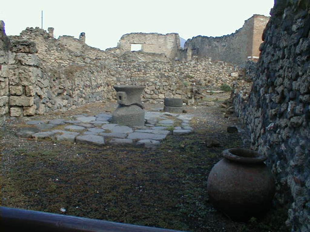 VII.16.6 Pompeii. September 2004. Looking north across workshop, at the rear was a doorway into VII.16.9. According to Eschebach, the doorway on the left would have led into a small room under the steps at VII.16.5.
At the rear on the left would have been a stairs to the upper mezzanine, with a latrine beneath. In the workshop were two dolia, three mortars, and two or three mills.
See Eschebach, L., 1993. Gebudeverzeichnis und Stadtplan der antiken Stadt Pompeji. Kln: Bhlau. (p.347)
