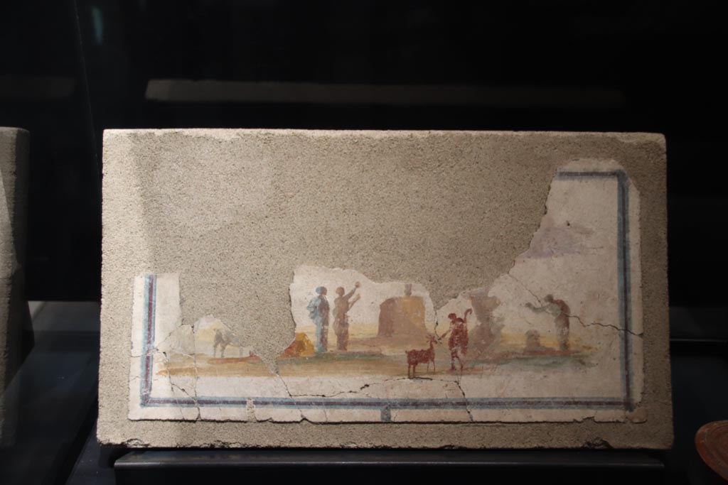 VII.16.a Pompeii. Suburban Baths. March 2024. The exhibition card only says this landscape is from the Suburban Baths. We do not know the exact location.
Photo courtesy of Giuseppe Ciaramella.
Fresco showing Sacred idyllic landscape, 54-68 AD. (Paesaggio idillico sacrale, 54-68 d.C)
On display in exhibition in Palaestra entitled – “L’altra Pompei, vite comuni all’ombra del Vesuvio”.
PAP inventory number 41667.

