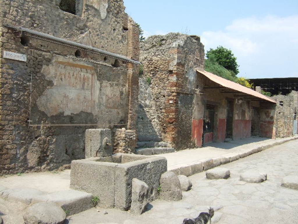 IX.11.1 Pompeii. May 2006. Looking north-east along Via dellAbbondanza towards house with street shrine and fountain, left. and Thermopolium of Asselina, right. According to Della Corte, written on the street shrine above the altar with the last sacrifice in honour of the 12 gods, were the names of the Vicomagistri, reading  
Successus, Victor
Asclepiades, Co(n)sta(n)s      (Vicomagistri)        [CIL IV 7855]
See Della Corte, M., 1965.  Case ed Abitanti di Pompei. Napoli: Fausto Fiorentino. (p.307)

