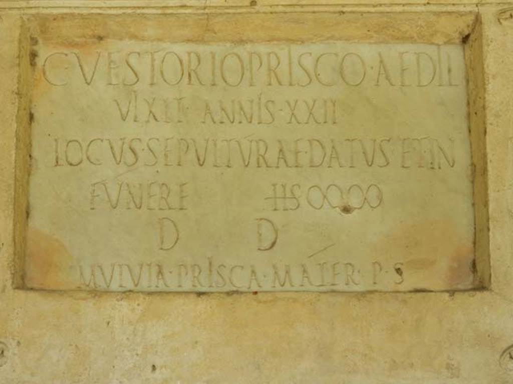 VGJ Pompeii. May 2015. Detail of inscription on east side. Photo courtesy of Buzz Ferebee.  The inscription reads:- 

C(aio) VESTORIO PRISCO AEDIL(i)
VIXIT ANNIS XXII
LOCVS SEPVLTVRAE DATVS ET IN 
FVNERE SESTERTIUM DUO MILIA 
d(ecreto) d(ecurionum)
MULVIA PRISCA MATER P(ecunia) S(ua)

See La Rocca, E, de Vos, M & E, & Coarelli, F. (1981): Guida archeologica di Pompei. Milan: Mondadore (P.280)

According to Virginia L. Campbell, this expands to

C(aio) Vestorio Prisco aedil(I)
Vixit annis XXII
Locus sepulturae datus et in 
funere (sestertium) duo milia 
D(ecreto) D(ecurionum)
Mulvia Prisca mater p(ecunia) s(ua)

See Campbell V. L., 2014. The tombs of Pompeii: Organisation, Space, and Society. Abingdon UK: Routledge, p. 98.

According to Cooley, this translates as -

To Gaius Vestorius Priscus, Aedile. 
He lived 22 years. 
His burial place was granted along with 2,000 sesterces for his funeral by decree of the town councillors.  
Mulvia Prisca, his mother, set this up at [her own] expense.
 
See Cooley, A. and M.G.L., 2004. Pompeii: A Sourcebook. London: Routledge. (F88, p. 128).  
