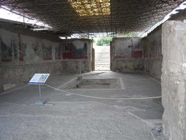 Stabiae, Villa Arianna, September 2015. Room 18, looking north-east across tablinum towards Vesuvius.
According to the onsite description board, a large part of the mosaic flooring was removed in the Bourbon era and was recomposed in a hall of the Naples Archaeological Museum. The preliminary sketch of the mosaic was brought to light in the 1950’s.
