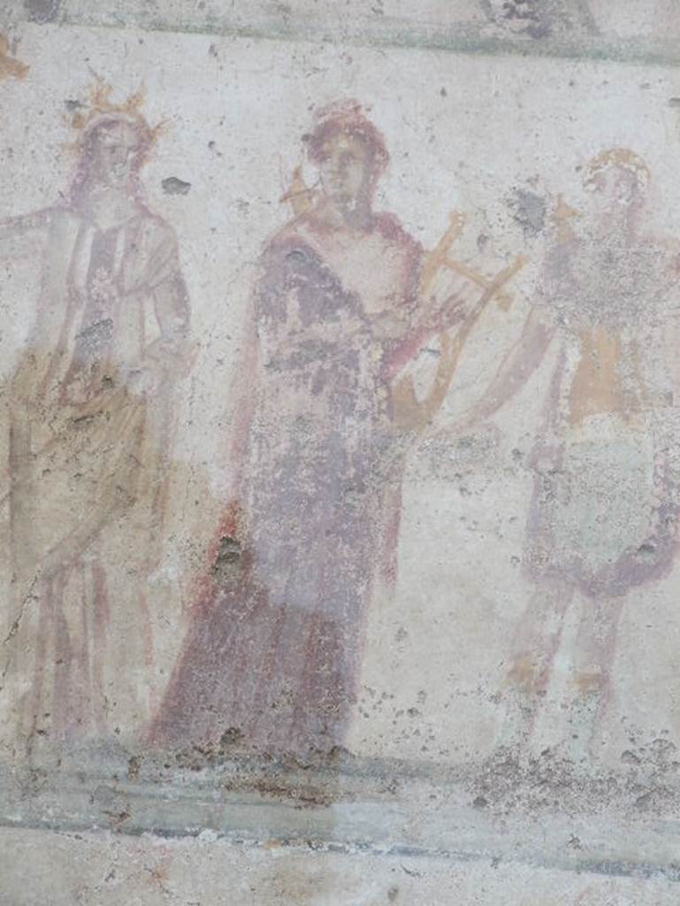 Detail of Apollo outside IX.11.1.  December 2006.  Apollo: Hair tied in knot, quiver behind shoulder, in brown Chiton and red coat, walking right but with head turned left, cithara held in left arm. See Lararien und Fassadenbilder in den Vesuvstadten by Thomas Frohlich, F66, page 335-337.