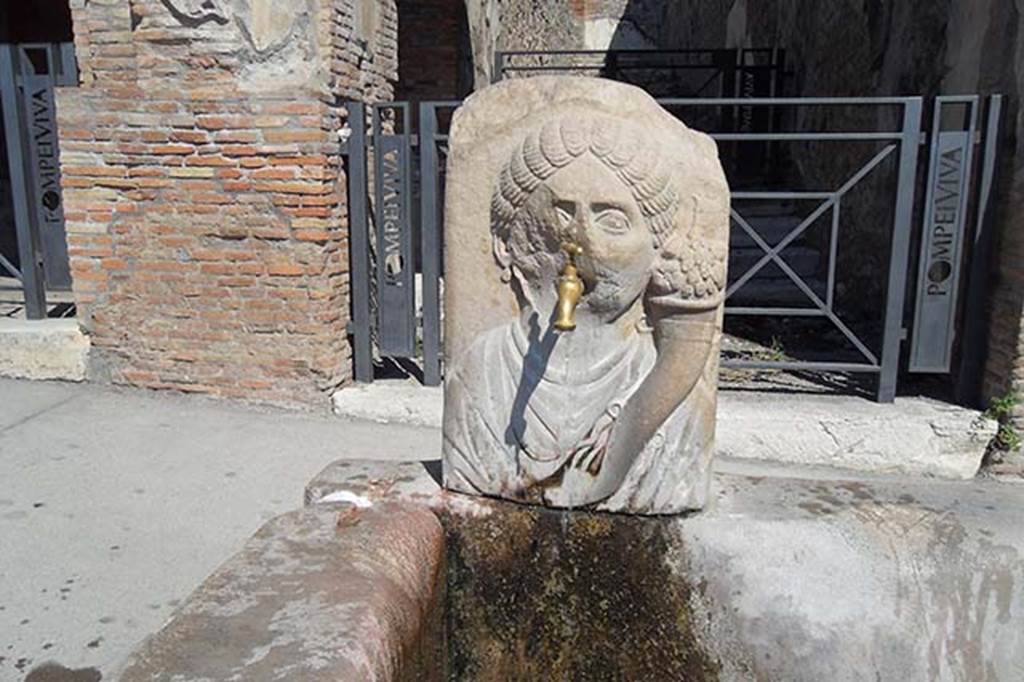 Fountain outside VII.9.67 and VII.9.68. September 2013. Relief of head of Fortuna (Abbondanza) with cornucopia. The fountain has now acquired a tap. Photo courtesy of Brigitte and Gert Watzel.