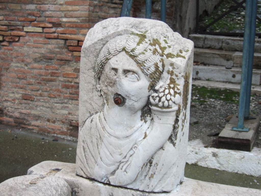 Fountain outside VII.9.67 and VII.9.68. March 2009. Relief of head of Fortuna (Abbondanza) with cornucopia.
