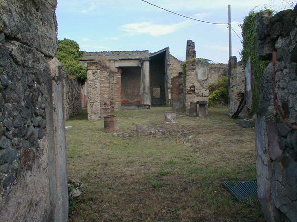 VII.7.10 Pompeii. September 2004. Looking north across atrium, from entrance fauces.
According to Boyce, against the west wall of the tablinum, near the entrance from the atrium, stood a high masonry base upon which may have rested the lararium.
See Boyce G. K., 1937. Corpus of the Lararia of Pompeii. Rome: MAAR 14. (p.68, no.297) 
