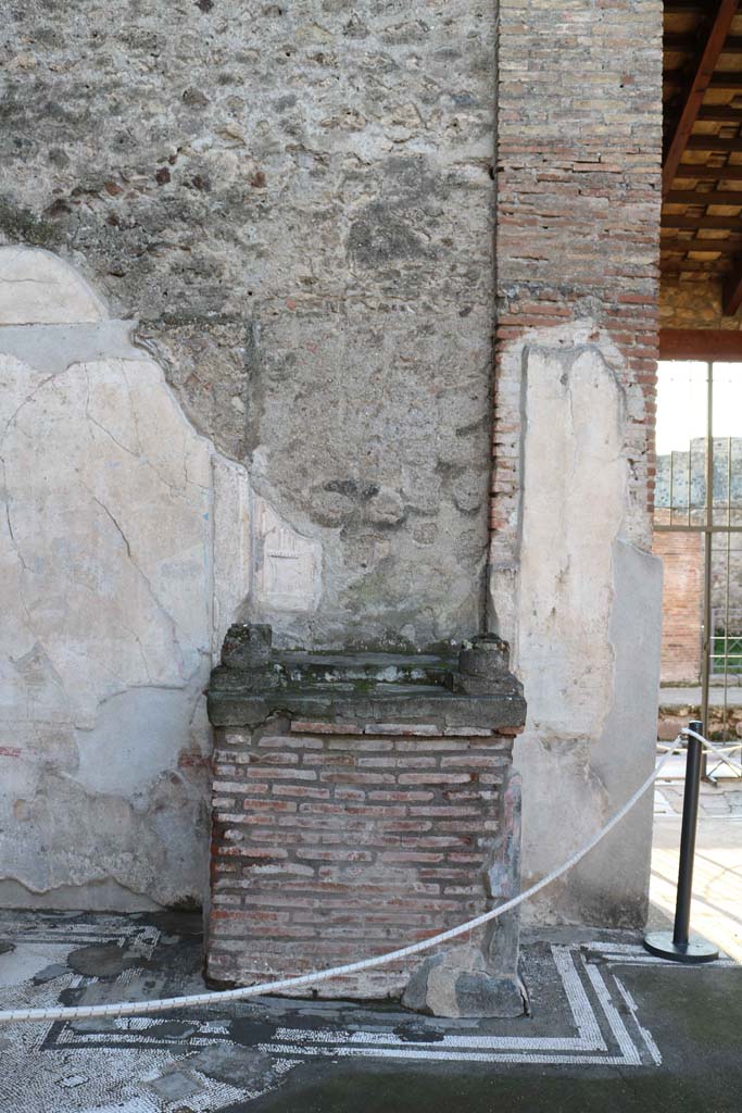 IX.3.5 Pompeii. December 2018. 
Room 3, looking west to remains of aedicula altar in south-west side of atrium. Photo courtesy of Aude Durand.
According to Boyce –
The aedicula, of which now only remains the rectangular podium (1.20 by 0.83, h.1.10) and the bases of the two columns which supported the roof over the shrine. The podium is coated with stucco and painted in imitation of marble and in the centre of each side is a painted wreath.
The whole structure was richly ornamented with mouldings of coloured stucco.
See Boyce G. K., 1937. Corpus of the Lararia of Pompeii. Rome: MAAR 14. (p.83, no.408).
See Giacobello, F., 2008. Larari Pompeiani: Iconografia e culto dei Lari in ambito domestico. Milano: LED Edizioni, (p.249, no.A38)
