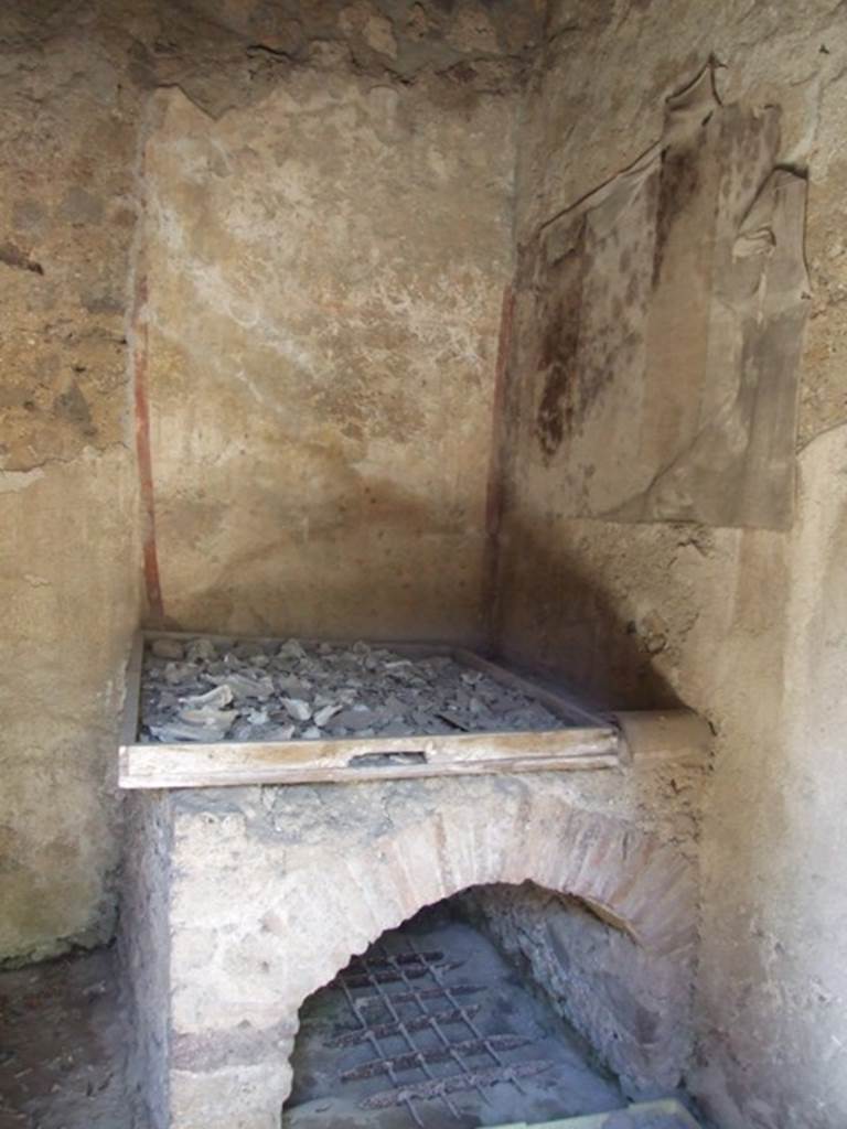 I.12.8 Pompeii. March 2009. Room 10, north-west corner of kitchen with lararium. On the north wall can just be seen some cloth, which has adhered to the lararium and damaged it. 
It used to show one serpent approaching a round altar from the right.  See Giacobello, F., 2008. Larari Pompeiani: Iconografia e culto dei Lari in ambito domestico.  Milano: LED Edizioni.  (p.152-3). According to Curtis, the lararium painting covering two walls above the oven in the kitchen was beautiful but badly-deteriorated. Painted on the north wall was a large single serpent near an altar. On the altar were sacrificial gifts, such as pine cones.
There may have been another scene beneath the serpent, but the wall was too badly damaged to verify this. See Curtis, R.I: The Garum shop at Pompeii, In Cronache Pompeiane, V,1979, (p.20-1)
