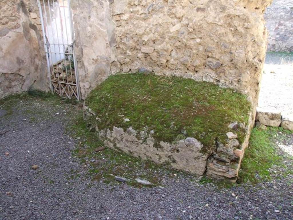 V.2.i Pompeii. December 2007. Room 11, looking towards west wall in kitchen.  
According to Mau above this bench or hearth were the remains of a painting of the 2 Lares.  
Near them a serpent was seen coiled around an altar, on which was a large pine cone.
See Mau, A., 1907, translated by Kelsey F. W. Pompeii: Its Life and Art. New York: Macmillan. (p.307).
Boyce also mentioned that a man was leading a reluctant hog.
He also said the lower zone was not well preserved and only a few traces of the foliage remained, through which the usual serpents must have glided.
See Boyce G. K., 1937. Corpus of the Lararia of Pompeii. Rome: MAAR 14. (p.38, no.109). 

