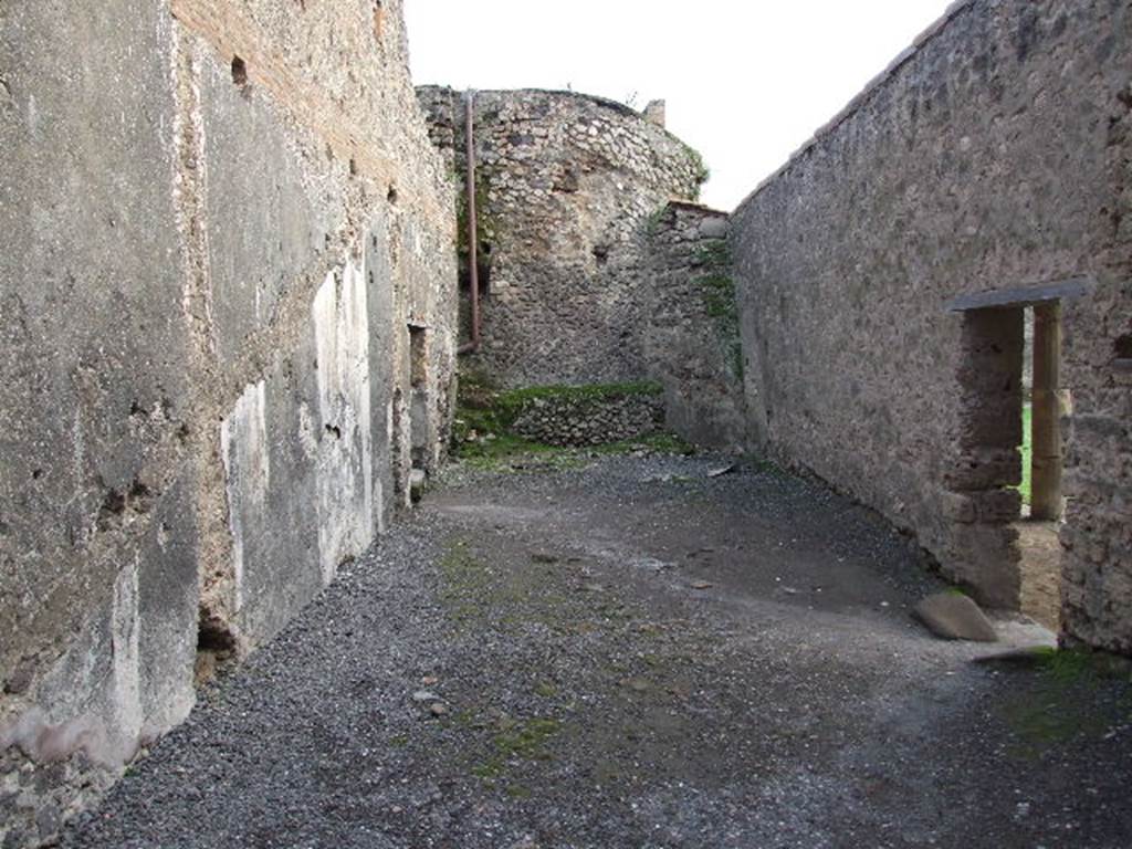 VII.1.8 Pompeii. December 2007. Room 8, anteroom of women’s baths, looking south from changing room 11. Doorway leading to praefurnium 7 is on left. Doorway to east portico B and gymnasium C is on right. According to Boyce, on the east wall (left), was a painted single serpent coiling towards an altar with offerings. He described it as being above the small arched opening that passed the conduit that supplied water for the labrum of the women’s calidarium 9. This would be somewhere in the vicinity of the large white patch on the wall. See Boyce G. K., 1937. Corpus of the Lararia of Pompeii. Rome: MAAR 14.  (p. 95, 472).
 
