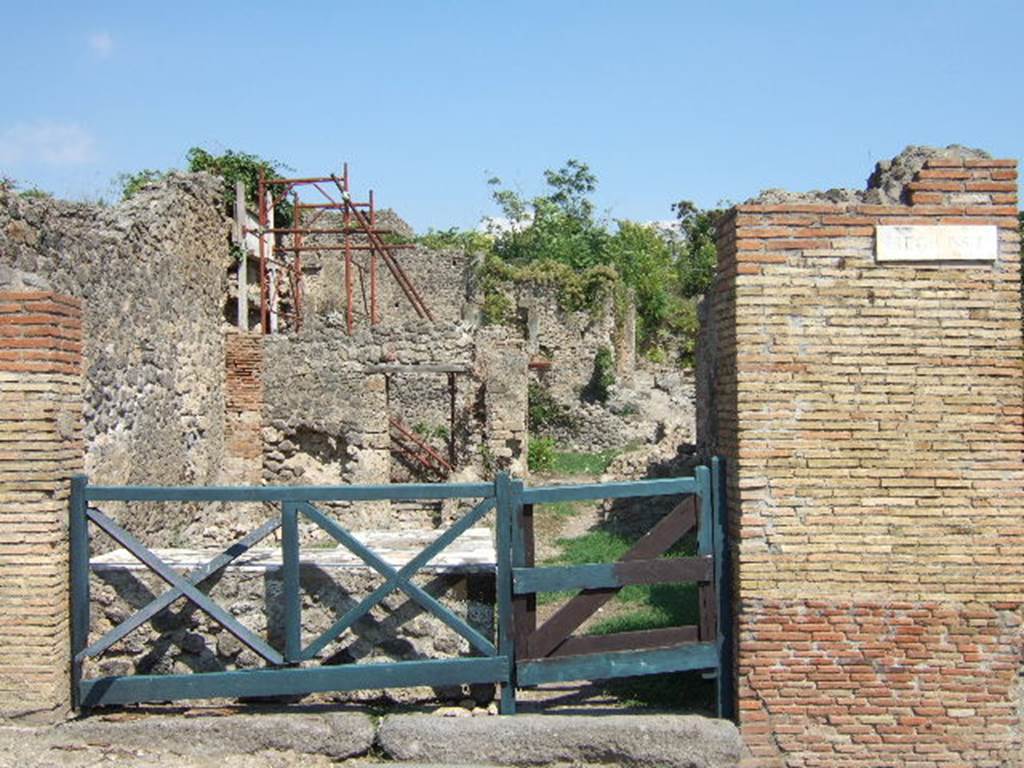 I.2.1 Pompeii. May 2005.  Entrance with marble topped counter on north (left) side, on the south side was a hearth.  At the rear, the remains of two rooms can be seen, with another rear room east behind the rear room on north side (with scaffolding).
