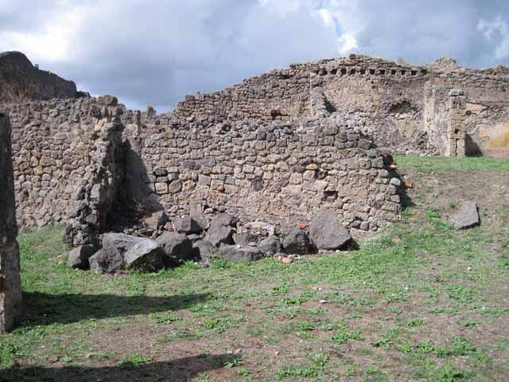 1.2.3 Pompeii. September 2010. Looking north towards remains of north wall (left or north-western corner of atrium). The shop at I.2.4 is on the left behind the wall.  The north wall of house at I.2.6 can be seen at the rear. Photo courtesy of Drew Baker.
