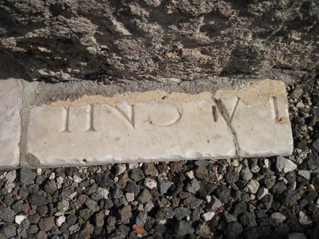 I.3.3 Pompeii. September 2010. Detail of marble fragment with inscription near east wall of atrium at south end of the threshold. Photo courtesy of Drew Baker.
