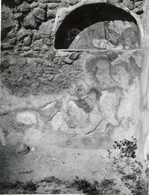 I.3.5 Pompeii. September 2010. Detail of niche in rear east wall on south side. Photo courtesy of Drew Baker. According to Boyce, this broad arched niche in the east wall, originally had its walls coated with white stucco. The stucco was painted with red, blue and green flowers and plants. Eventually, a layer of red stucco was spread over the top, and since peeling off, had revealed the earlier layer underneath. See Boyce G. K., 1937. Corpus of the Lararia of Pompeii. Rome: MAAR 14. (p.24) 

