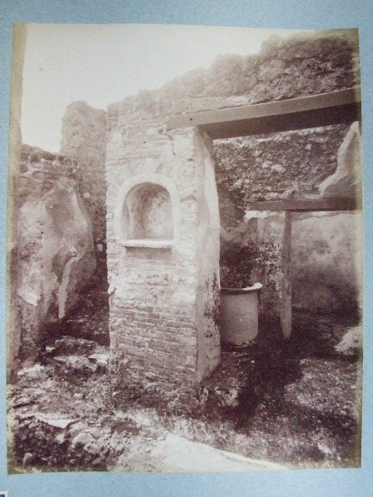 I.3.30 Lararium in peristyle at foot of straight flight of stairs. Old undated photograph courtesy of the Society of Antiquaries, Fox Collection.
According to Boyce, in the west wall of the peristyle was an arched niche. Its walls were adorned with painted flowers. On the wall on either side of it, was painted a Lar, 34cms high, holding rhyton and situla. Below it, there was a single serpent moving towards an altar.
See Boyce G. K., 1937. Corpus of the Lararia of Pompeii. Rome: MAAR 14. (p. 24) 

