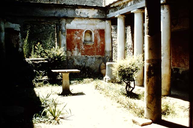 I.7.7 Pompeii. 1961. Lararium niche in west wall in north-west corner.  Photo by Stanley A. Jashemski.
Source: The Wilhelmina and Stanley A. Jashemski archive in the University of Maryland Library, Special Collections (See collection page) and made available under the Creative Commons Attribution-Non Commercial License v.4. See Licence and use details.
J61f0807
According to Boyce, the arched niche was adorned with a stucco aedicula façade and a cornice running around the inside walls. The area of the wall immediately around the niche was painted as part of the decoration, into which the niche was set in a panel. There was no lararium painting and no other indication of religious use. It is called an edicoletta larare in the report and probably was a shrine, as there was no other in the house.
Not. Scavi, 1927, 27.
See Boyce G. K., 1937. Corpus of the Lararia of Pompeii. Rome: MAAR 14. (p.25, no.39) 
