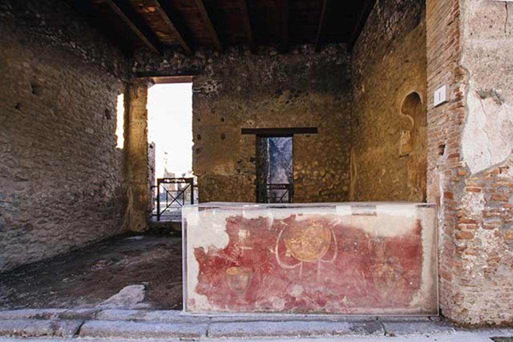 I.8.1 Pompeii. December 2018. Looking south towards shop counter. 
The shop counter shows a yellow shield or clypeus and Bacchus motifs on a red background. Photo courtesy of Aude Durand.
