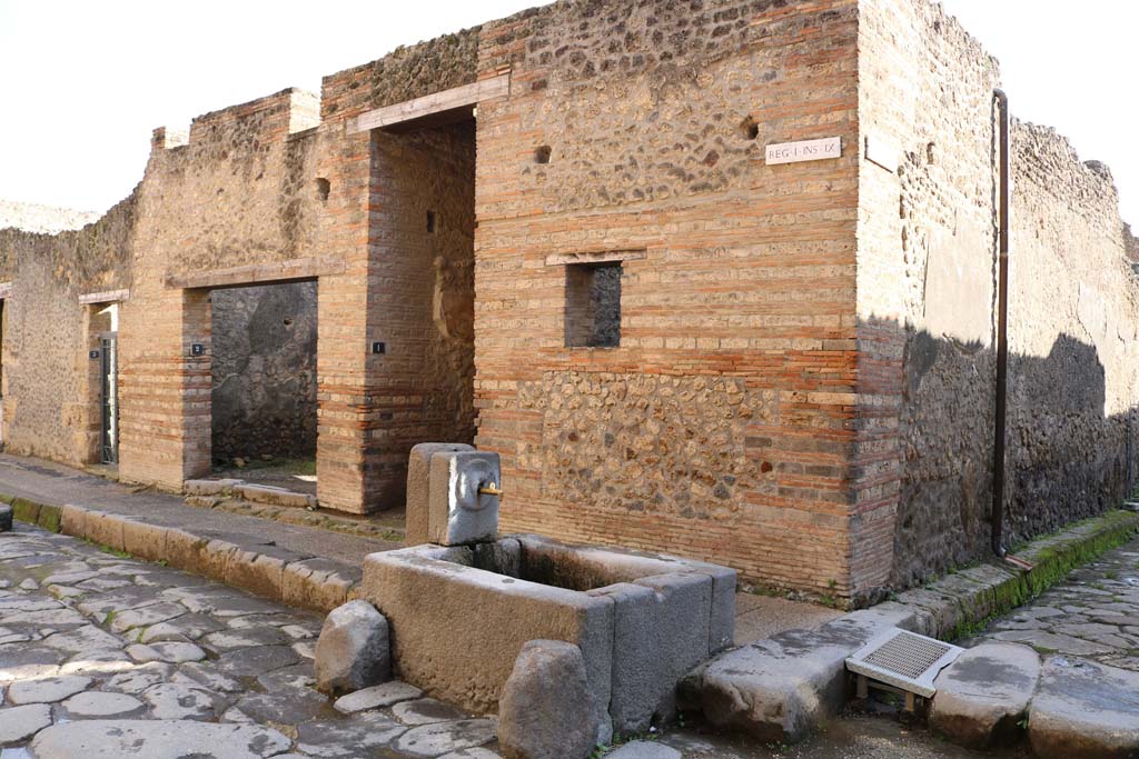I.9.1 Pompeii, December 2018. 
Looking south-east on Via dell’Abbondanza towards doorway at the rear of the fountain. Photo courtesy of Aude Durand.
