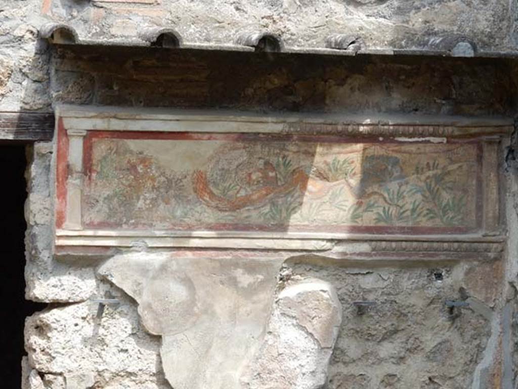 I.11.11 Pompeii. May 2017. Lararium on north wall of thermopolium. Photo courtesy of Buzz Ferebee.
A stucco border surrounding a serpent moving left to a round altar. In the background are green plants with red flowers.  See Fröhlich, T., 1991. Lararien und Fassadenbilder in den Vesuvstädten. Mainz: von Zabern. (L21, T:14,1:24,2).
