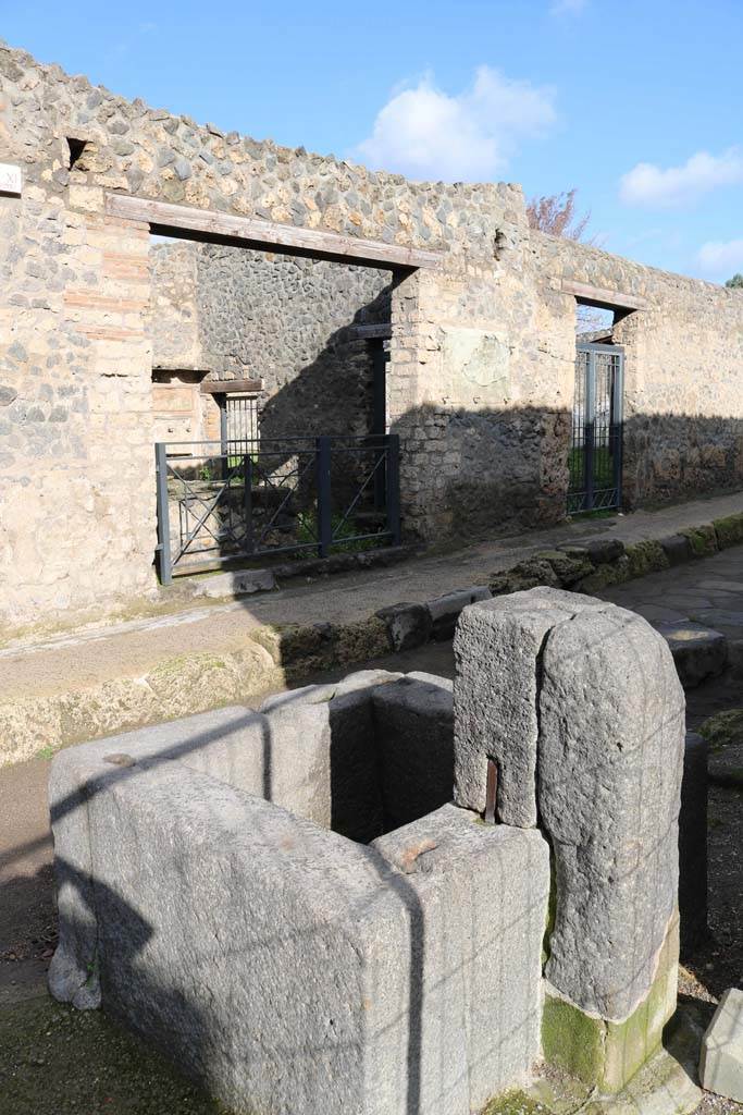 I.11.11 and I.11.10, Pompeii. December 2018. 
Looking towards entrance doorways on north side of Via di Castricio, from fountain outside of I.16.4. 
Photo courtesy of Aude Durand.
