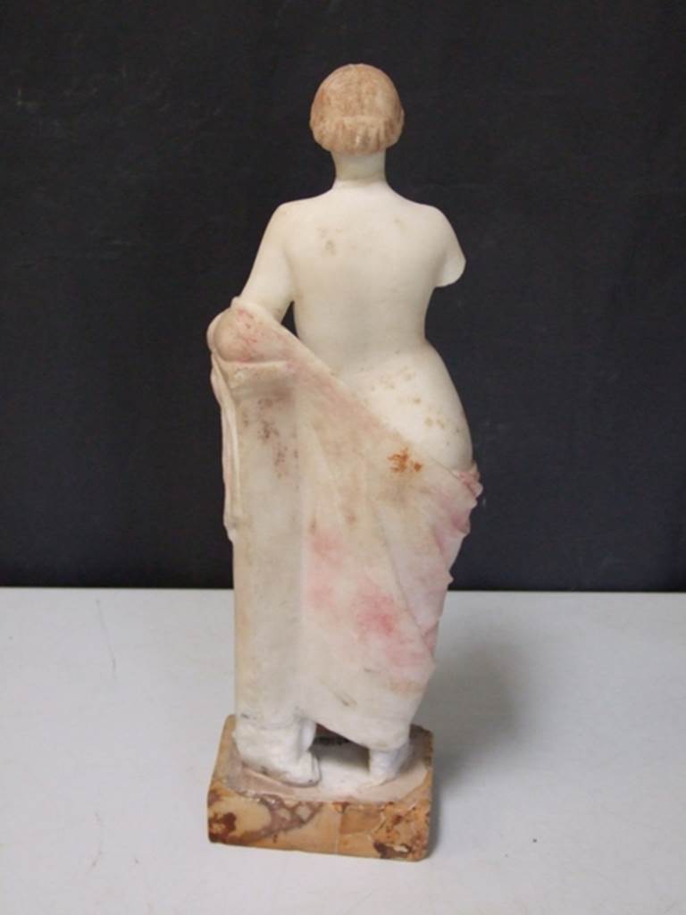 I.11.12 Pompeii.  March 2009.  White marble Venus statuette.  Rear view of drapery, still with colour. Found 1958 in the Aedicula Niche on the south wall of the garden.  SAP Inventory number: 12164.
