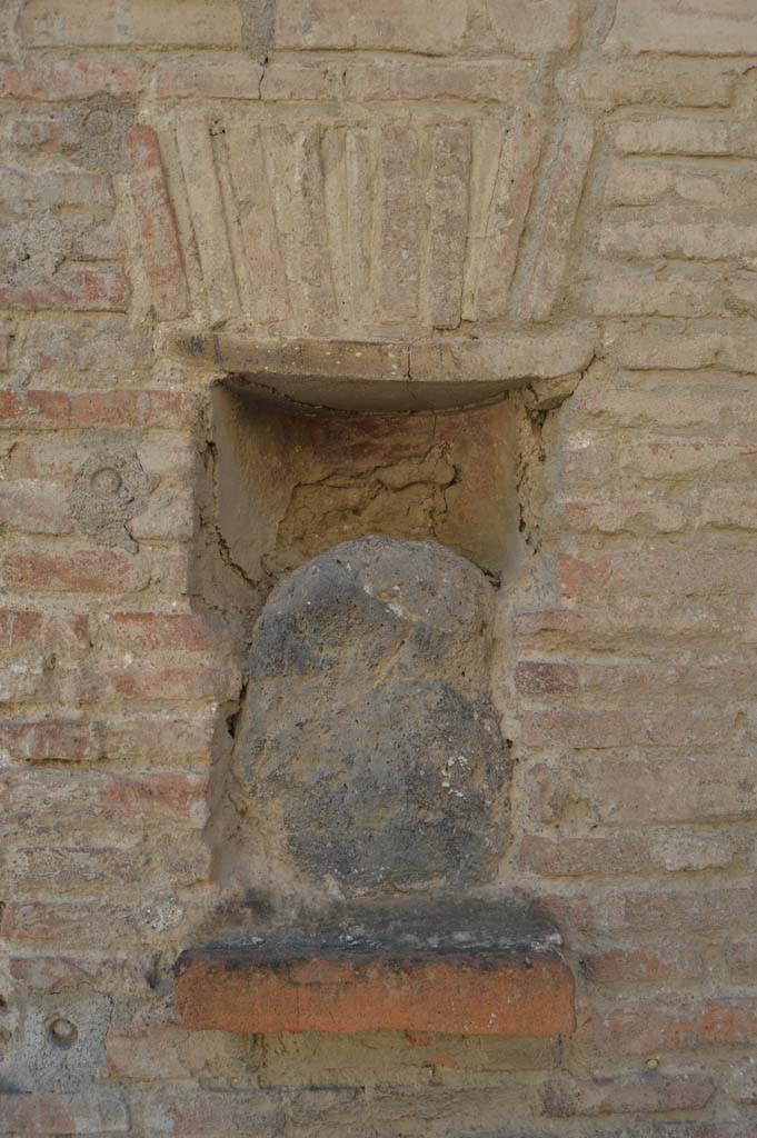 Street shrine or niche outside I.12.5 Pompeii. September 2005. This is on Via dell’ Abbondanza, at the corner with Vicolo dei Fuggiaschi. According to Della Corte, on the red pilaster which ended the insula on the east side, two electoral programmes were found.
The first – GAVIVM II VIR.
The second was immediately below the first  - AMPLIATUM  L F AED
                                                                                                                  VICINI                                                                                                           
                                                                                                             SVRGITE ET
                                                                                                             ROGATE
                                                                                                             LVTATI F[ac]     
The text was placed towards the right, because the pilaster was interrupted in the middle by a rectangular niche.
In the niche was fixed a coarse, rough stone resembling the outline of a human head, not the usual marble bust, as often seen here and there in the street.
See Notizie di Scavi, 1914, (p.204)
According to Epigraphik-Datenbank Clauss/Slaby (See www.manfredclauss.de), these are numbered CIL IV 7442 and CIL IV 7443.
According to PPM, inserted in the rectangular niche on the left side of the doorway was a blue lava stone, which had been a “lava-bomb” erupted during a prehistoric eruption and which was supposed to have been attributed with sacred and magical values. This was inserted into an apsed rectangular niche, with the lower level consisting of a tile projecting by about 6 cm and closed into the upper area by another tile with architrave under a flat arch in brick. 
See Carratelli, G. P., 1990-2003. Pompei: Pitture e Mosaici. Vol. II.  Roma: Istituto della enciclopedia italiana. (p.736)
