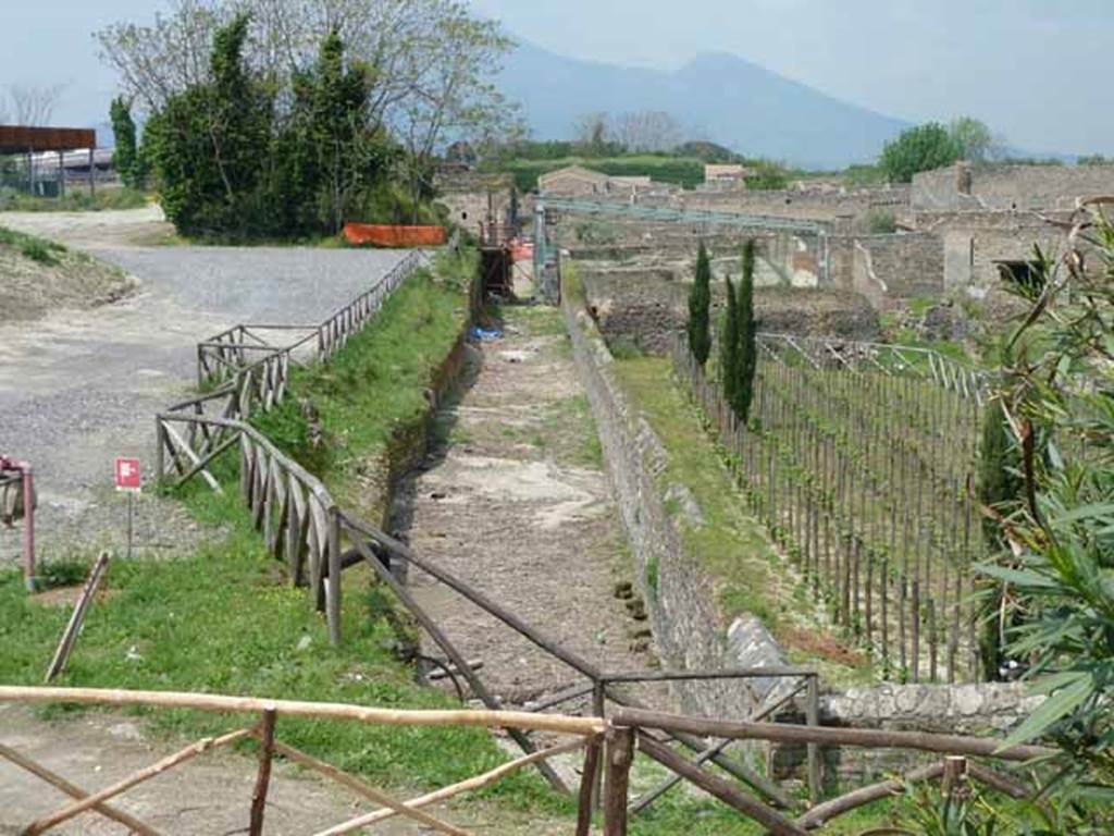 1.23 Pompeii, on the left. May 2010. Looking north along roadway between I.23 and I.22.   1.22.1 is on the right hand side of the far end of the insula, under the blue girders.
