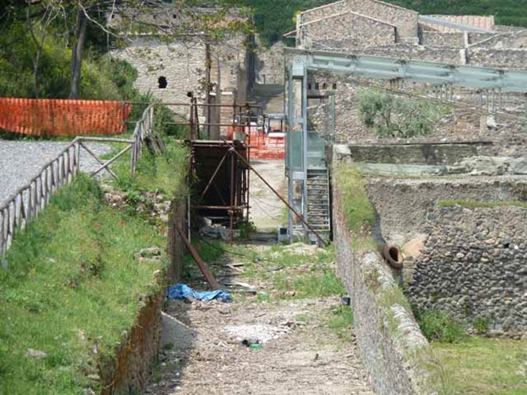 1.23 Pompeii, on the left. May 2010. Looking north along roadway between I.23 and I.22.   1.22.1 is on the right hand side, in the centre of the photo under the blue girders.


