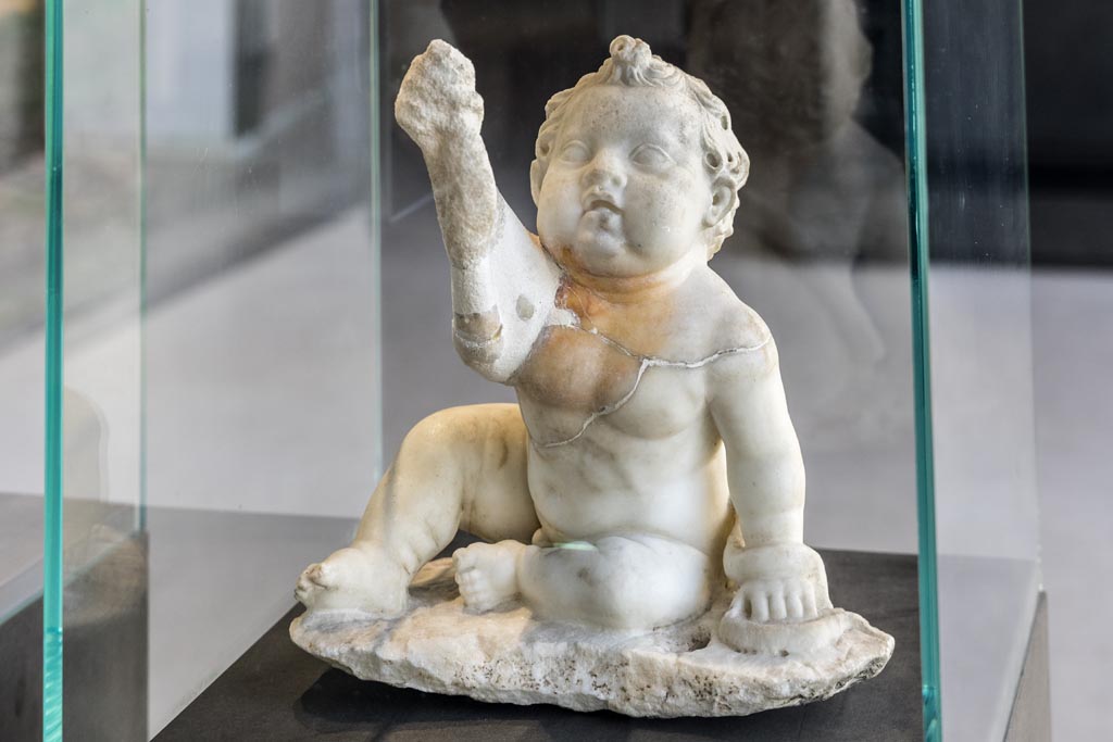 II.2.2 Pompeii. January 2023. Room “i”. White marble statuette of a young Hercules strangling a snake.
Found on the north side of the upper euripus in the garden in 1920. On display in exhibition in Palaestra. Photo courtesy of Johannes Eber.
