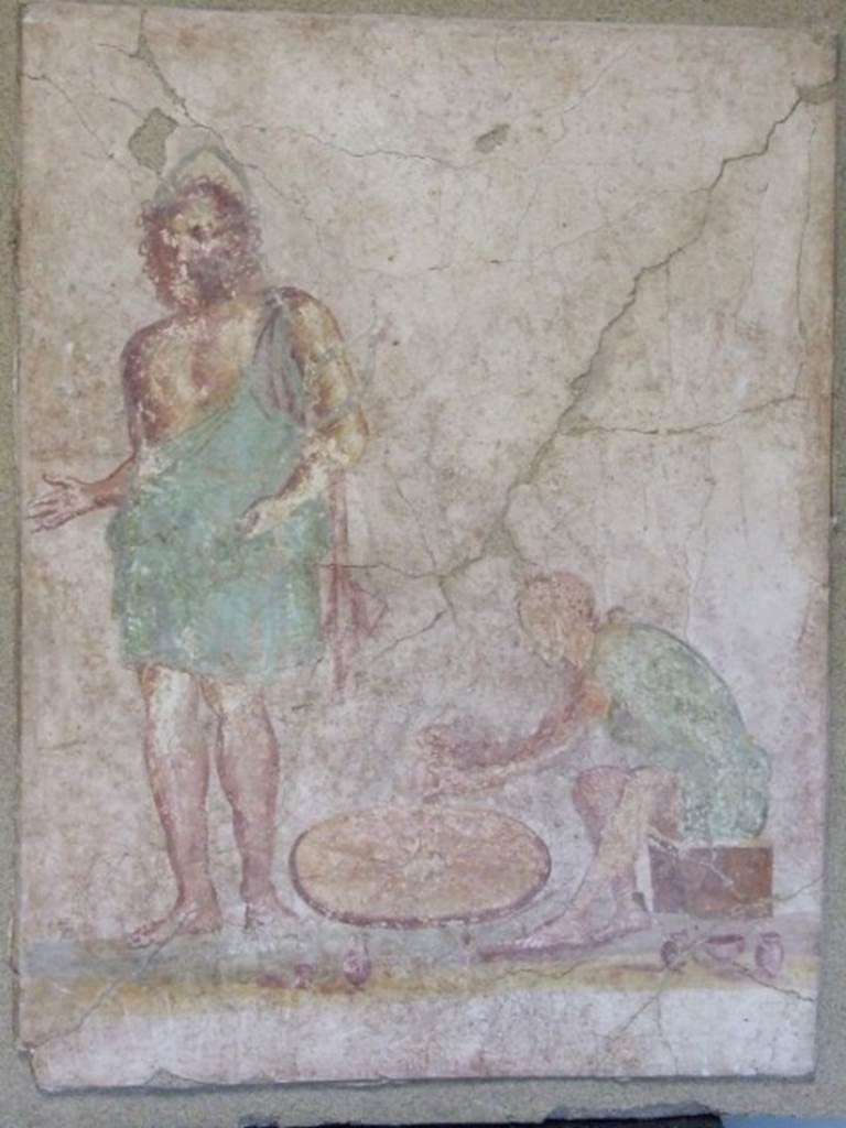 II.3.8 Pompeii.  Painting of a God, possibly Vulcanus or Hephaistos, and potter at his wheel.  found on the outside of the south-west corner of the shop.   SAP Inventory number 21631.