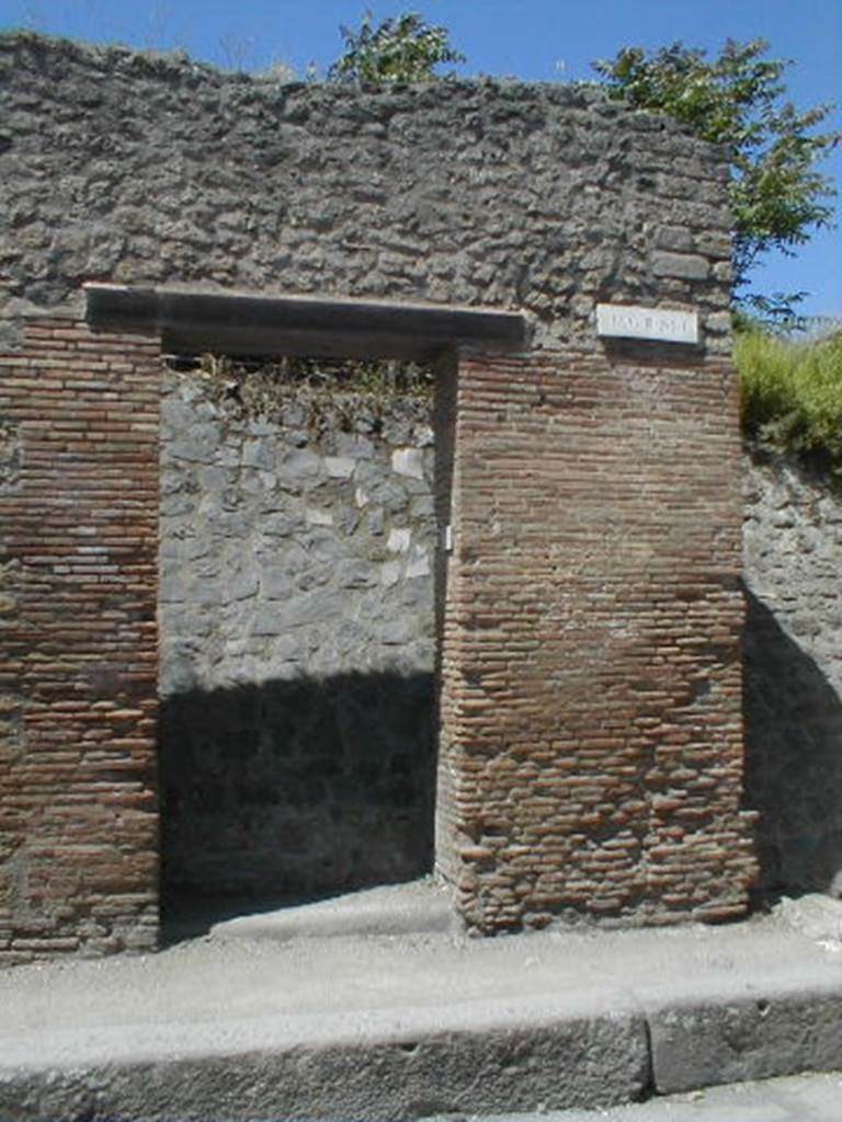 III.1.6 Pompeii. May 2005. Entrance doorway, partly excavated
According to Della Corte, an obscure Praedicinius practiced his unknown commerce or industry here.
He came to this conclusion because of the graffito found on the pilaster on the right -
Popidium adulescentem
Praedicinius rog(at) aed(ilem)    [CIL IV 7608]
See Della Corte, M., 1965.  Case ed Abitanti di Pompei. Napoli: Fausto Fiorentino. (p.342)
According to Garcia y Garcia, there was slight damage to the south-east corner of this insula, when a bomb fell onto the Via dell’Abbondanza in 1943. The bomb fell in front of the SE corner of this insula, between III.1.6 and I.XI.7.  See Garcia y Garcia, L., 2006. Danni di guerra a Pompei. Rome: L’Erma di Bretschneider. (p.51)

