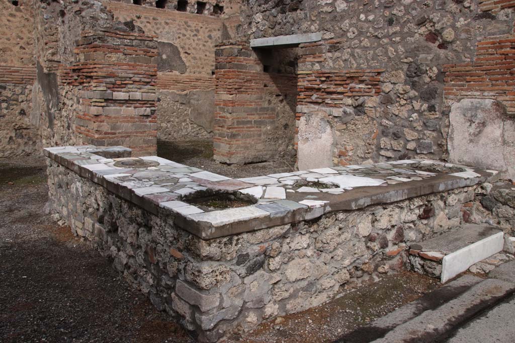 V.1.1 Pompeii. October 2020. Looking across counter with hearth from entrance on Via di Nola. Photo courtesy of Klaus Heese.