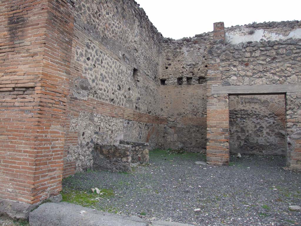 V.1.2 Pompeii. December 2007. West wall with podium for wooden bench? and steps to upper floor.