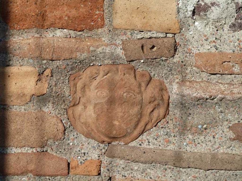 VI.1.4 Pompeii. September 2015. Terracotta mask of head embedded in masonry on south side of entrance doorway.

