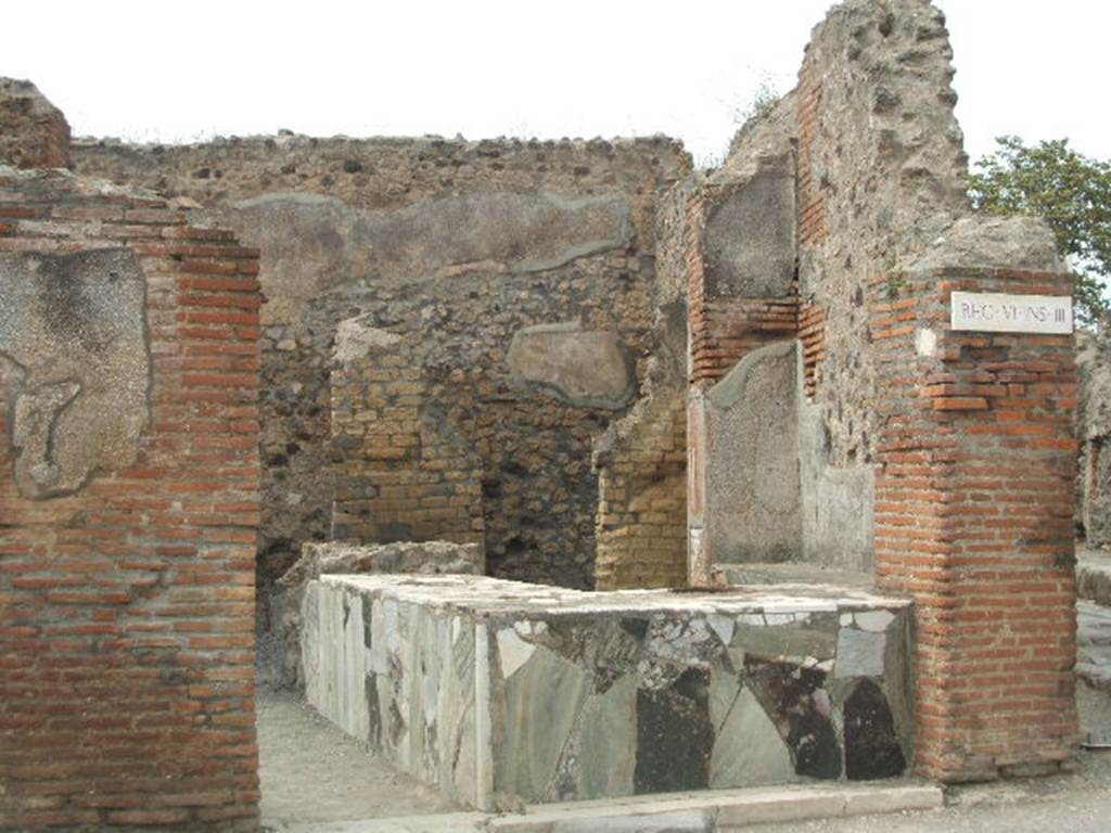 VI.3.20 Pompeii. May 2005. Looking north towards entrance doorway.
There used to be an electoral recommendation, found on the left of the doorway where remains of plaster can still be seen.
According to Della Corte, this is a thermopolium with two rooms annexed for the entertainment of the customers and a rustic room with a staircase leading to the upper floor.  
The manageress or owner was a woman, Fortunata, as proved by a painted programma near to one of the doors.
This showed Fortunata recommending the candidate M. Casellio Marcello.
See Della Corte, M., 1965.  Case ed Abitanti di Pompei. Napoli: Fausto Fiorentino, p. 42.
