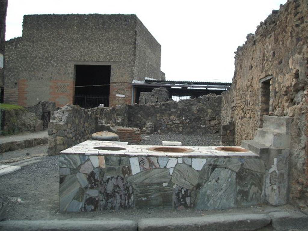 VI.4.8 Pompeii. December 2006. Sales counter, looking west to rear room. 
The entrance, VI.4.9 on Via delle Terme, can be seen on the south (left) side. According to Garcia y Garcia, this area was nearly all destroyed by the bombing in 1943. The bomb provoked the total fall of the walls, internal and external onto Via Consolare, between the north wall and on its east side.
See Garcia y Garcia, L., 2006. Danni di guerra a Pompei. Rome: L’Erma di Bretschneider. (p.75)
