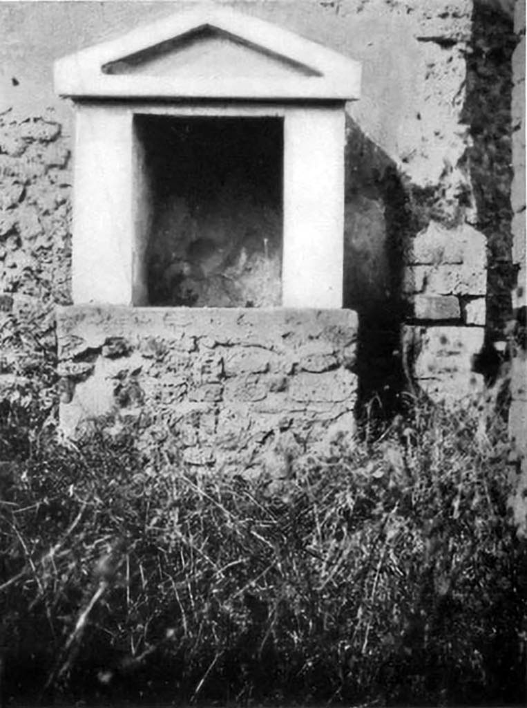 VI.5.14 Pompeii. 1930s photo of lararium by Tatiana Warscher.
According to Boyce, it had a solid base with two heavy walls forming a rectangular niche, surmounted by a gable roof with a simple pediment.
The walls inside were covered with unpainted white stucco.
In the floor was embedded a square block of marble, in which was cut a rectangular hole.
It was as if this was meant to hold the pivot upon which turned a door to close the shrine.
See Boyce G. K., 1937. Corpus of the Lararia of Pompeii. Rome: MAAR 14.  (p.46, no.154, and Pl.34,2)
See Giacobello, F., 2008. Larari Pompeiani: Iconografia e culto dei Lari in ambito domestico. Milano: LED Edizioni. (p.269)
