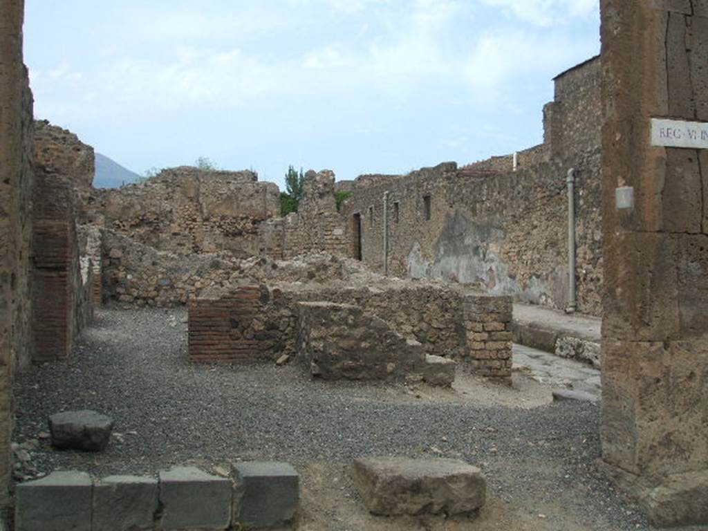 VI.6.4 Pompeii. May 2005. Looking north through entrance towards remains of rear wall with steps to upper floor. On the left is the doorway to a rear room. This bakery was damaged due to the bombing of 1943, when the south-east corner of the atrium of VI.6.1 and the nearby workshops were hit. On the right can be seen the doorway at VI.6.5. 
