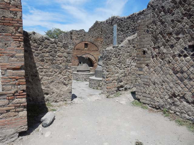 VI.6.17 Pompeii. May 2017. Looking towards north wall of entrance room with doorway to bakery. On the right is a doorway to a small rear room.  This small rear room may have been a storeroom for the flour, or possibly a stable for the animals used to turn the mills. Photo courtesy of Buzz Ferebee.
