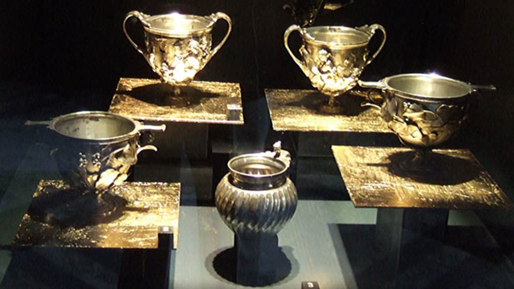 VI.7.20 Pompeii. Silver found on 23rd March 1835 in a room on the left (south) of the Tuscan atrium.
2 Canthari, cups with high handles, decorated with Centaurs and Amorini (rear). Inventory numbers 25376 (left) and 25377 (right).
2 Scyphi, deep oval cups with two handles, with ivy leaves decorations with traces of gilding (front right and left). Inventory numbers 25378 (left) and 25379 (right).
An olpe, a round mouthed oil flask or jug, with female head (front centre). Inventory number 25372.
Now in Naples Archaeological Museum.
See Pagano, M. and Prisciandaro, R., 2006. Studio sulle provenienze degli oggetti rinvenuti negli scavi borbonici del regno di Napoli.  Naples : Nicola Longobardi.  (p.150).
See Guzzo, P. (A cura di), 2006. Argenti a Pompei. Milano, Electa. (pages 114-122), figs. 106-109.
