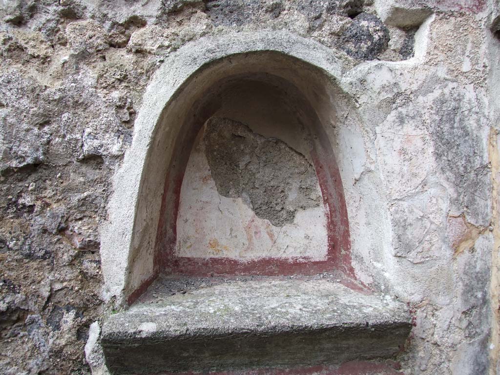 VI.7.23 Pompeii. December 2006. Kitchen, niche above household altar on north wall of kitchen.
According to Boyce, the inside walls were coated with white stucco, the corner outlined with broad red stripes.
Beneath it the floor projects from the surface of the wall.
On the back wall of the niche was painted the figure of the Genius, holding a patera with his right hand above a flaming altar.
The wall around the niche was covered with a panel of the same white stucco, bordered in red.
On each side of the niche was painted a Lar in yellow tunic and red pallium.
See Boyce G. K., 1937. Corpus of the Lararia of Pompeii. Rome: MAAR 14. (p. 48, no. 167, and Pl. 11,1) 
